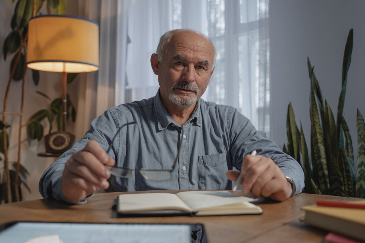 Aelterer Mann mit Notizbuch am Schreibtisch – Symbol fuer digitale Nachlassorganisation mit NutsAndNotes.